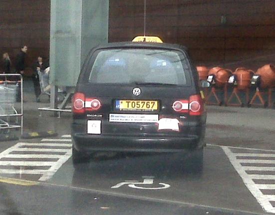 Taksi automobilis neįgaliesiems skirtoje vietoje