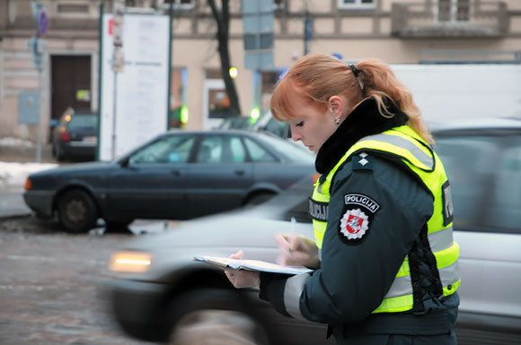 Asociatyvinė iliustracija: policijos pareigūnė fiksuoja avarijos aplinkybes.