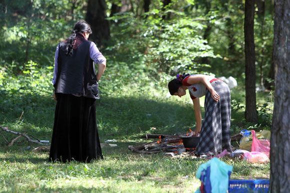 Nelegalioje stovyklavietėje moterys ruošia maistą.