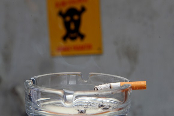 Smilkstanti ant peleninės krašto palikta cigaretė